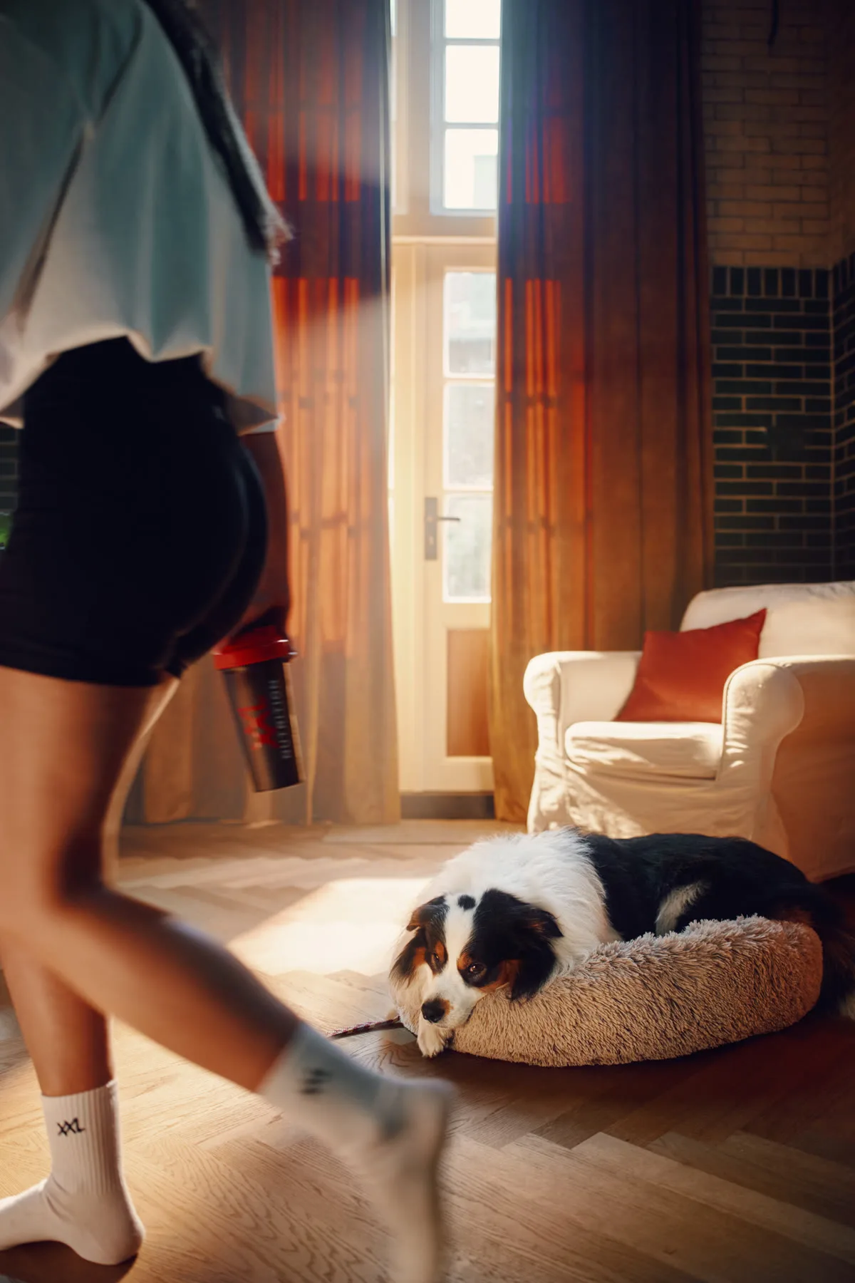 Baasje loopt in sportkleding langs de mand van een moe kijkende hond