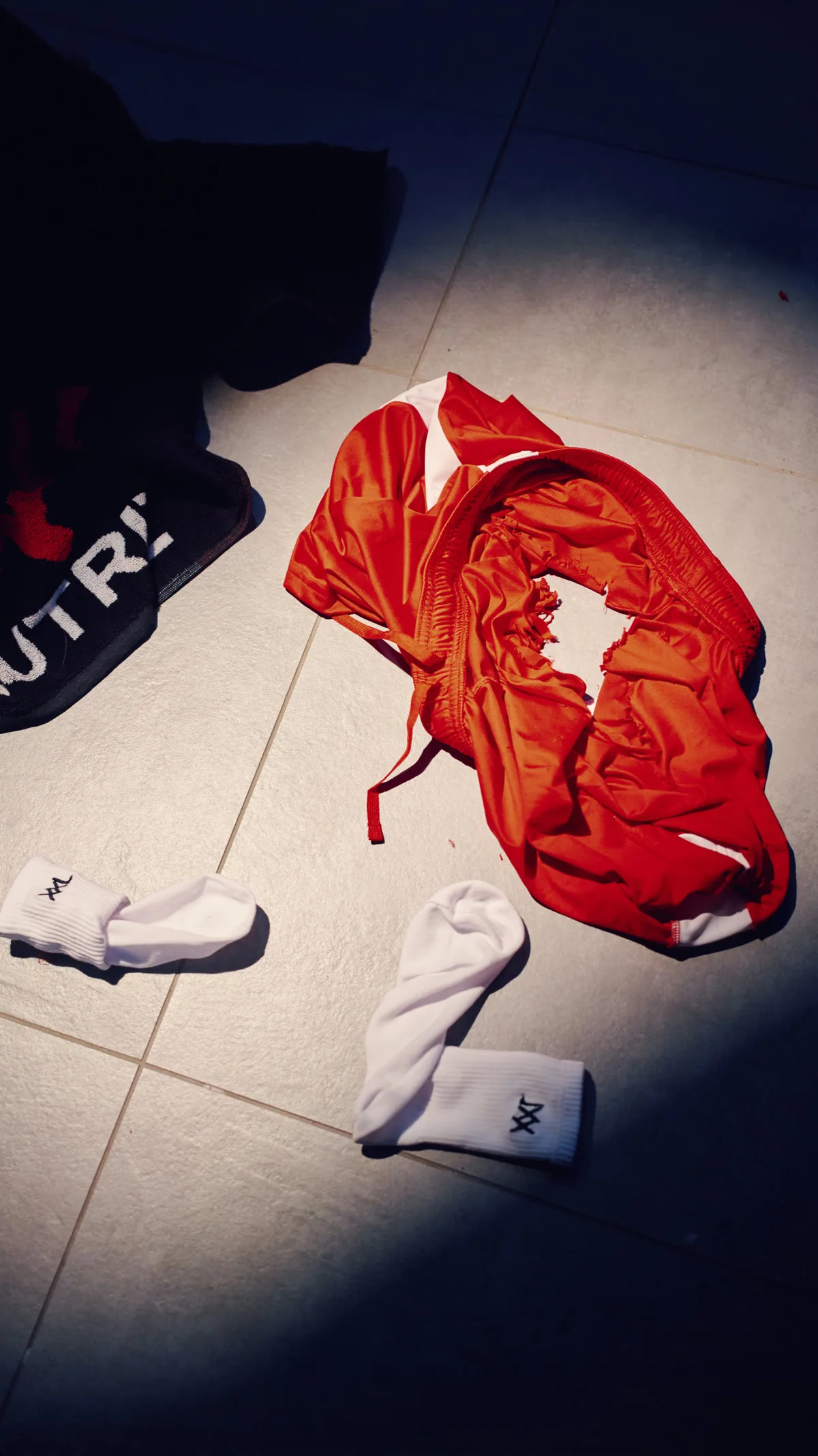 Rood sportshirt met een gat op een tegelvloer, staand formaat